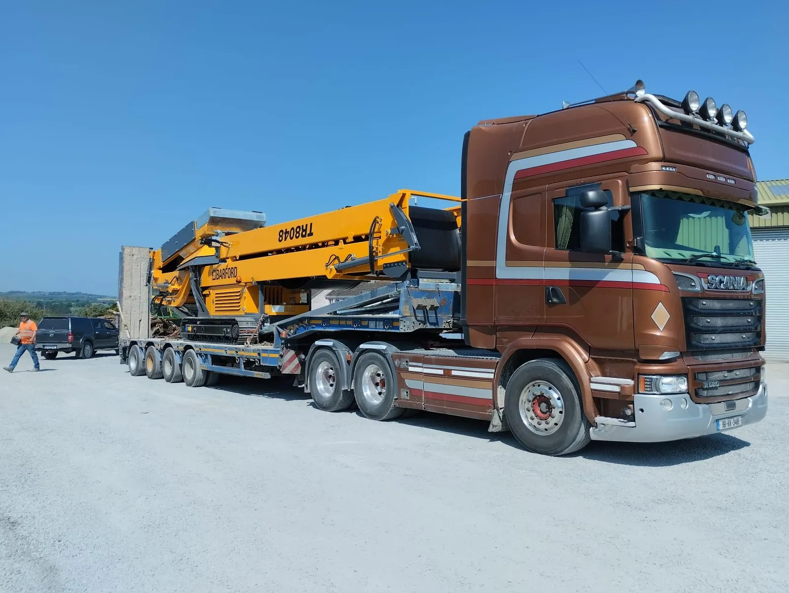 Truck hauling a tracked conveyor / stacker on a low-loader