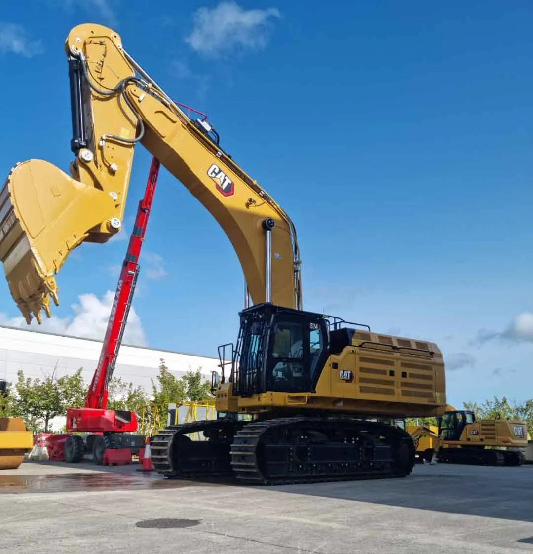 Large Caterpillar excavator with bucket raised, parked on a concrete pad