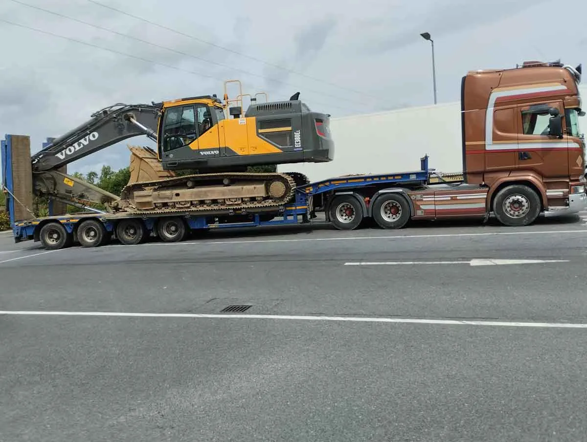 Excavator secured on a low-loader trailer on the road