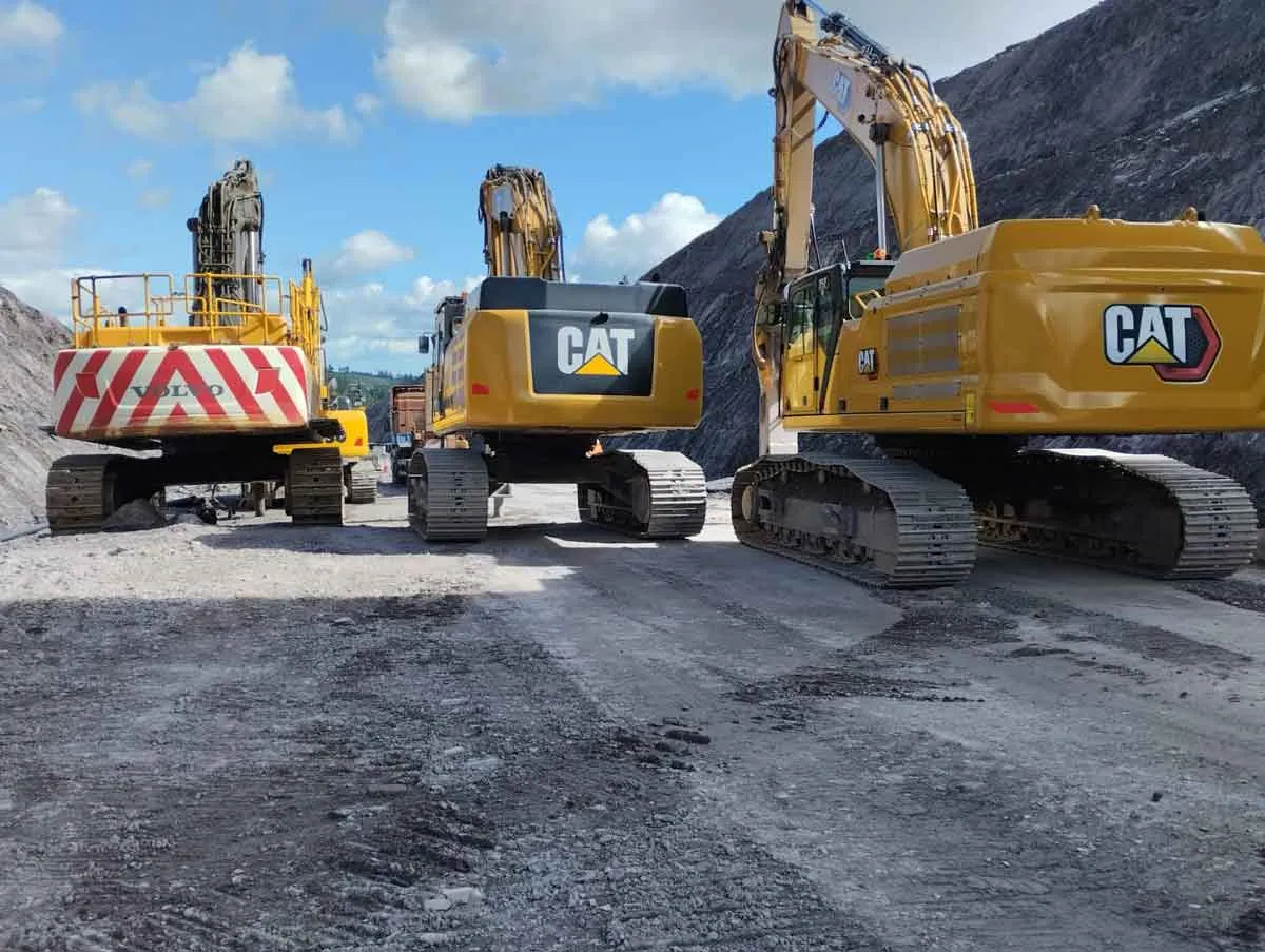 Lineup of heavy Caterpillar and Volvo excavators in a quarry