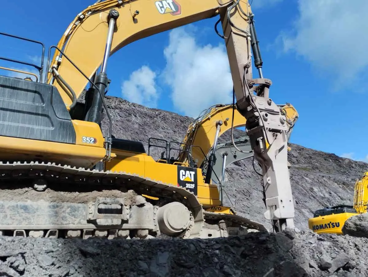 Caterpillar excavator using a hydraulic breaker on rock