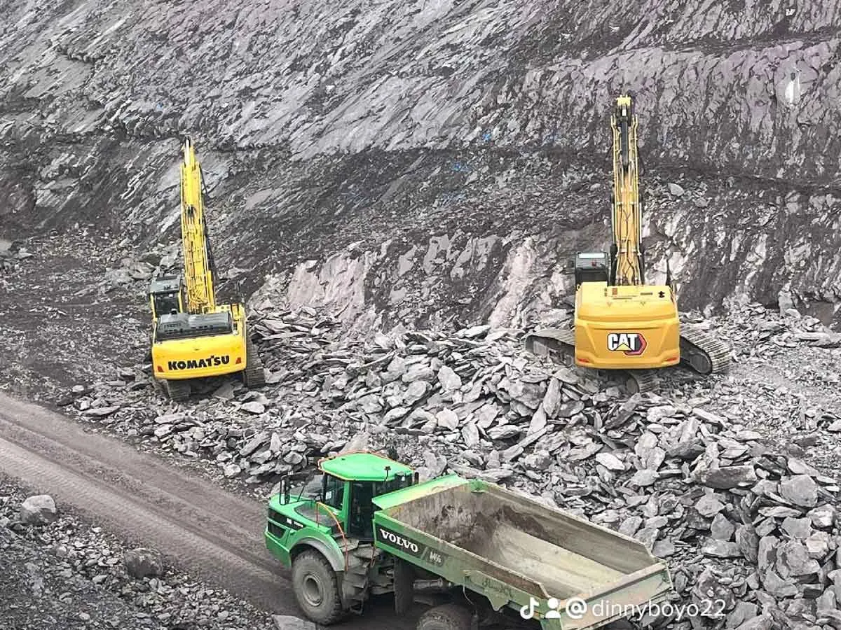Volvo articulated dump truck driving past excavators in a rocky quarry