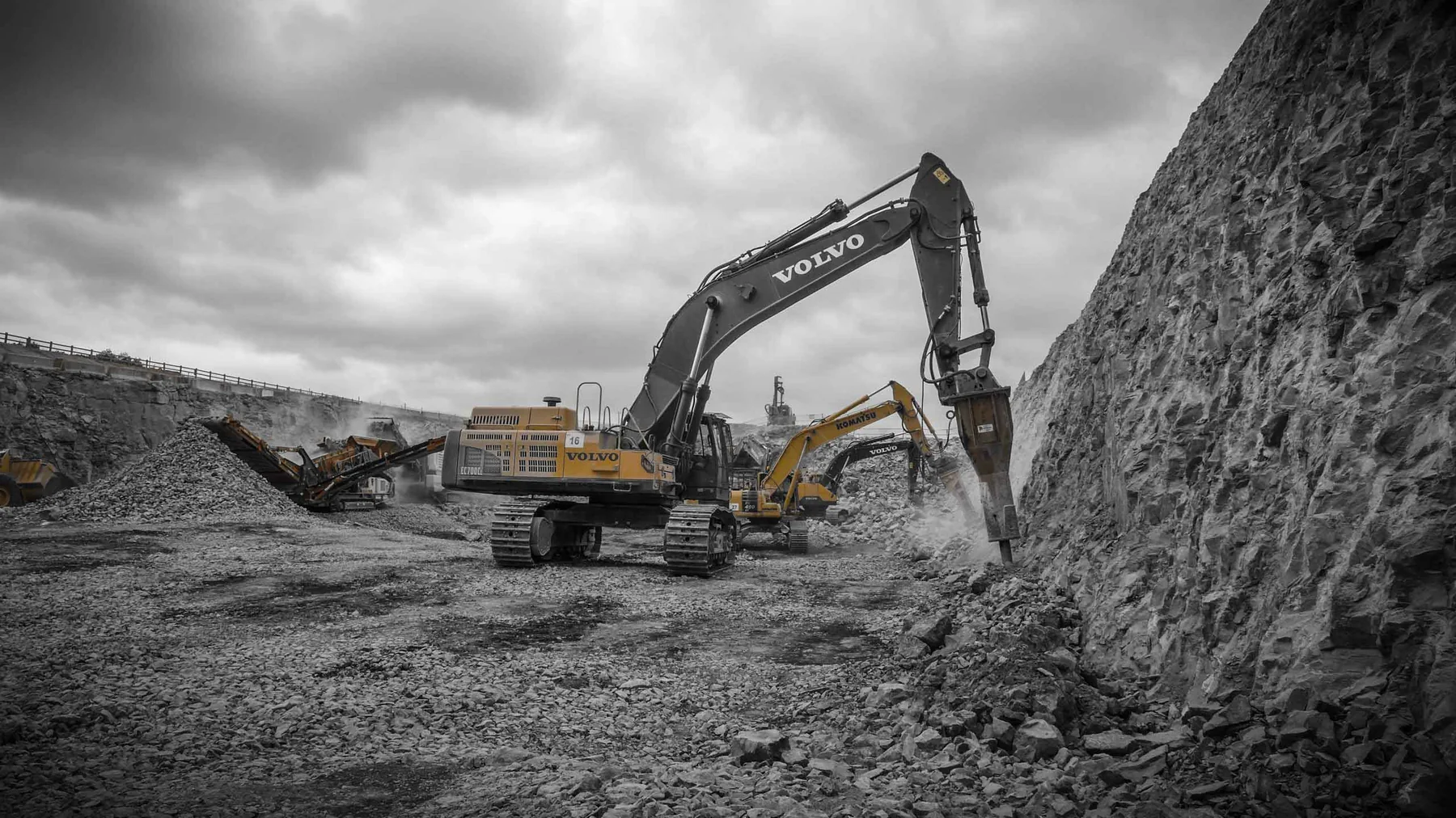 Heavy excavator and crushing plant working a quarry face